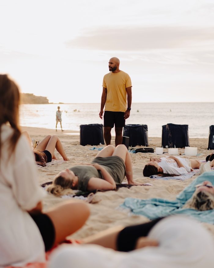 Navjot Matharu facilitating a sunset breathwork and sound bowl session on Bondi Beach